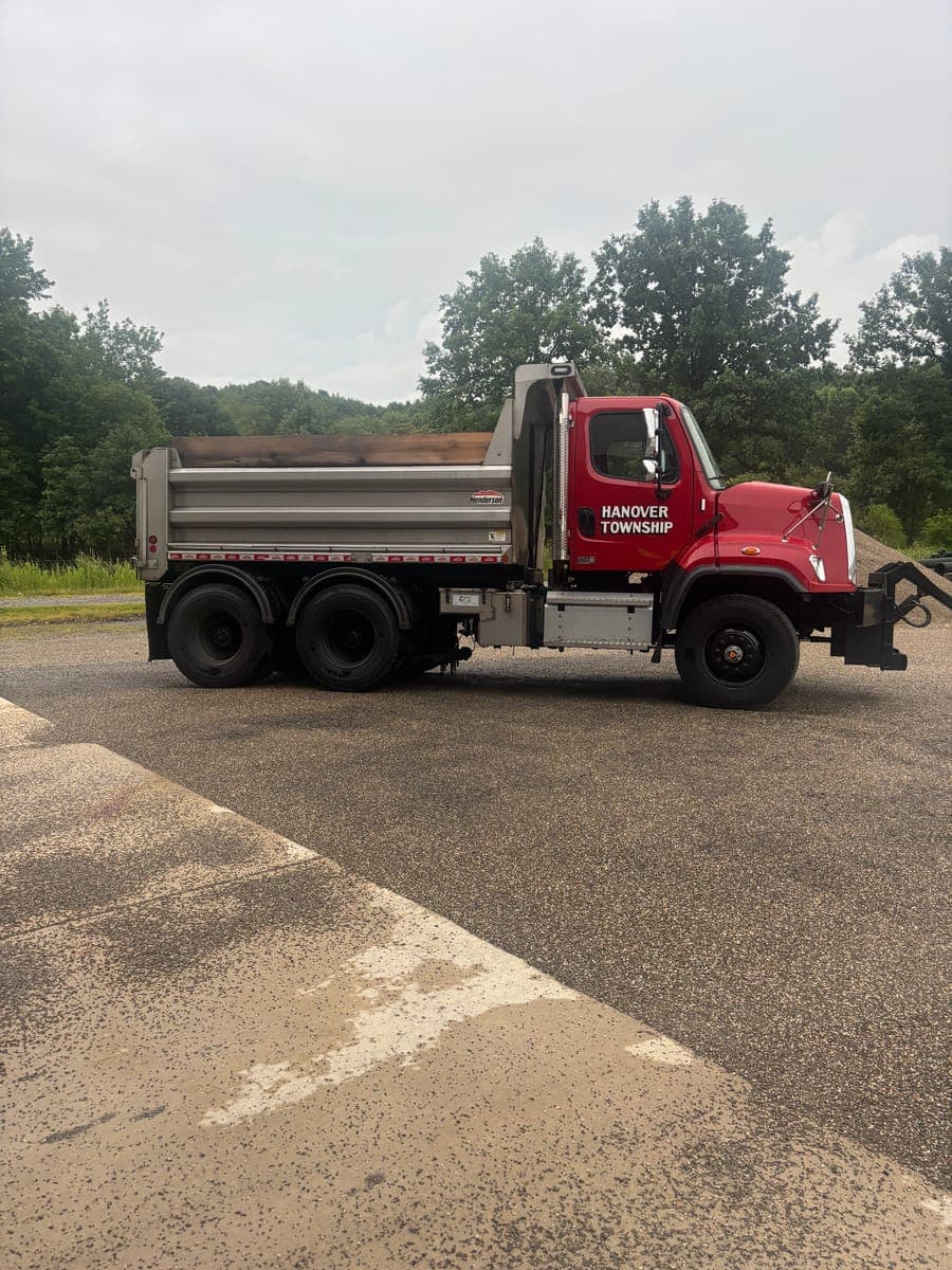 A Hanover Township dump truck with the plow frame mounted, parked at the township garage